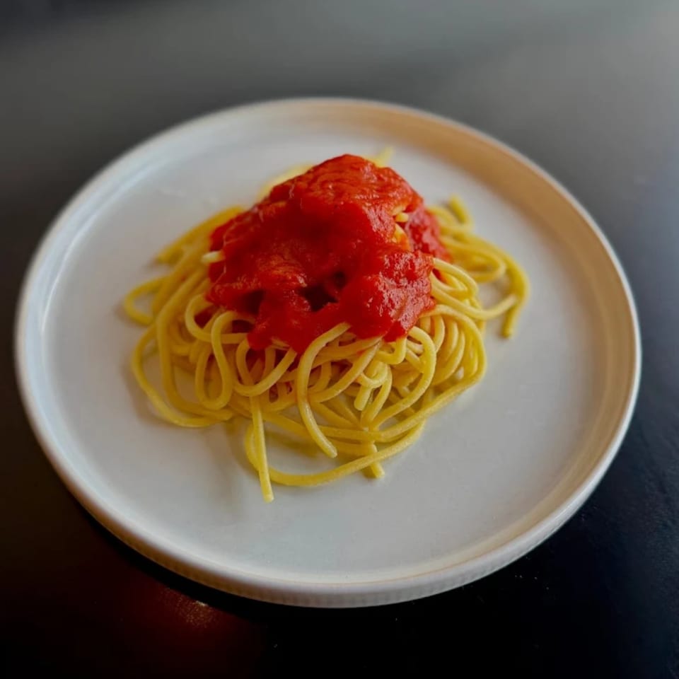 Spaghetti pasta with a vibrant red tomato sauce on a white plate.